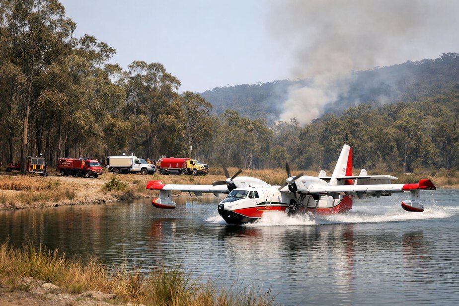 A firefighting helicopter refilling water near bushland.