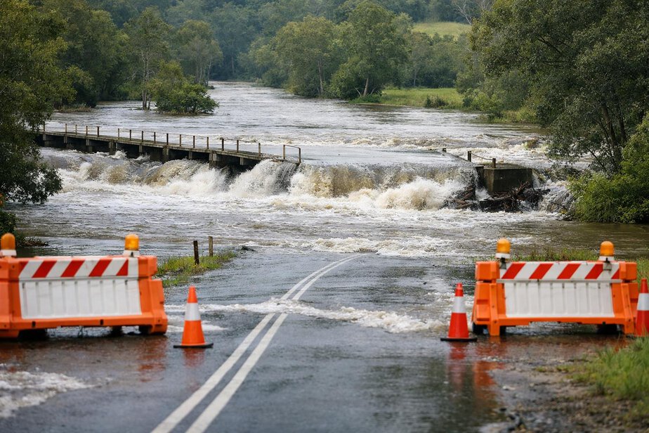 Floodwater covering a low road and bridge approach with barriers in place.