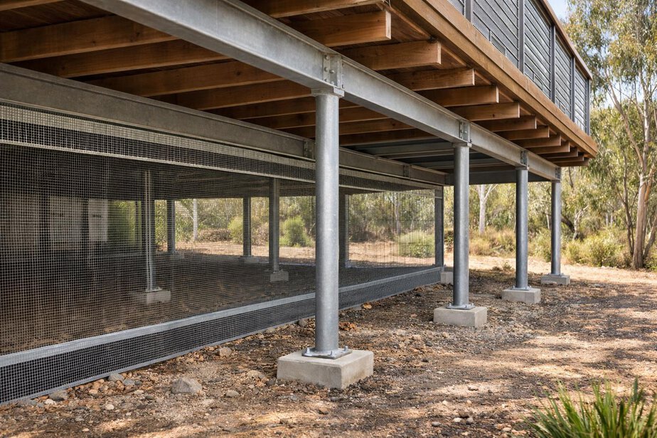 Raised home underfloor area protected with metal ember mesh and kept clear of stored combustibles.